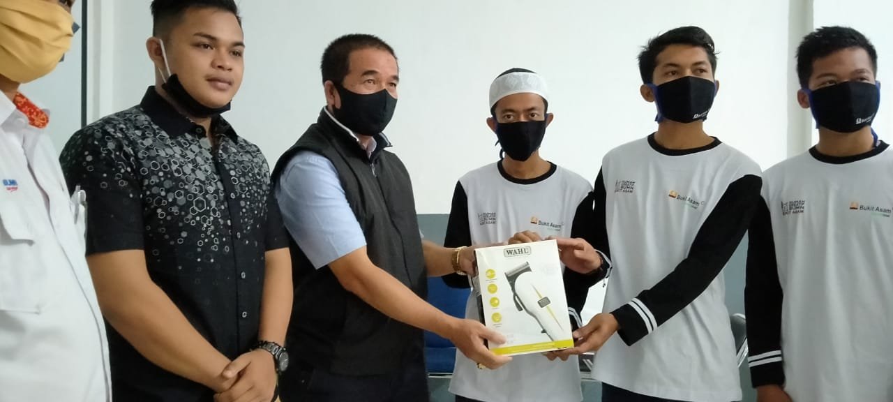 Manager keuangan CSR menyerahkan bantuan alat pangkas rambut